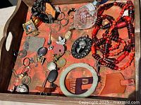 Overview of entire tray showing necklaces, crystal bottle, bangle and assorted small pieces