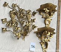 Gilt metal grapevine sconce and two gilt wood wall brackets laid flat on cloth