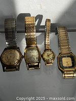 Four wristwatches side by side showing overall lot