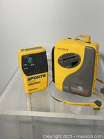 Front view of both yellow Sony Sports units and headphones