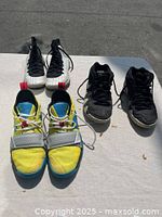 Three pairs Nike youth basketball shoes laid out: white/black pair, black pair, yellow/blue pair