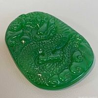 Front view of green jade pendant showing dragon carving