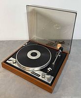 Turntable with lid open showing platter, tonearm and cord