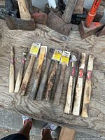 Full group of 10 hickory hammer handles on workbench