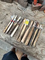 All ten hickory hammer handles laid out on workbench