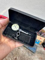 Dial indicator inside open black case held in hand