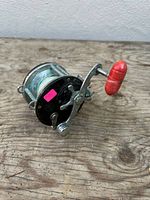 Right side view of reel showing red handle knob, star drag and pink sticker