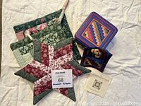 All items grouped: three potholders, star trivet, blue tin, toy horse, brochure