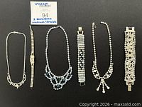 All six rhinestone jewelry pieces laid out on black background