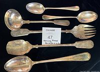 All six silver-plated serving utensils displayed