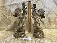 Front view of both cherub candlesticks with ruler for scale