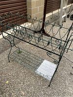 Full view of metal planter stand showing two tiers and scrollwork design