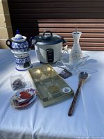 Overview of all kitchen items including teapot set, slow cooker, oil dispenser, gravy boat, spoon, strawberry slicer, boxed glass flutes