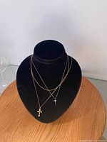 Three necklaces displayed on black bust