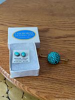 Stud earrings in branded box beside brooch