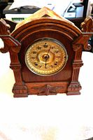 Front view of carved oak mantle clock showing brass dial and detached bezel