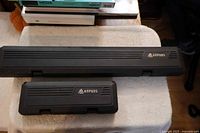 Two closed black Anpuds storage cases on table