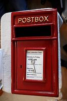 Front view of red cast iron post box showing mail slot, door and POSTBOX lettering