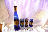 Full view of cruet with stopper and three glasses showing color and gilded bands