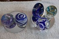Group of five glass paperweights displayed on mirror bases