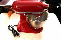 Front left view of red KitchenAid Artisan Mini stand mixer with bowl and whisk
