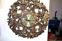 Front view of ornate gold plastic wall clock