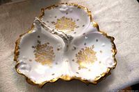 Overall view of white and gold three-section Limoges dish showing scalloped edges and central divider