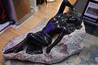 Front angled view of entire reclining figure on stone base