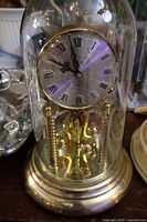 Full view of brass and glass anniversary clock under dome