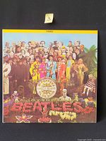 Front cover showing iconic Sgt. Pepper collage artwork with stereo banner
