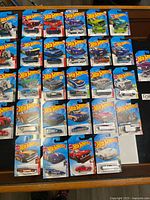 Overview of all 35 carded Hot Wheels vehicles laid out on table