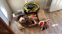 Group shot of carrier, playpen, plastic dome, baskets of toys, pillow, candle