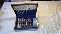 Open wooden chest showing full assortment of flatware pieces in blue felt interior