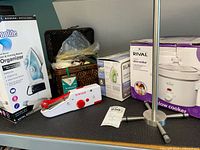 Group shot showing boxed slow cooker, boxed iron, boxed organizer, sewing basket and metal paper-towel holder