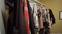 Garments on closet rod showing variety of blouses and outerwear