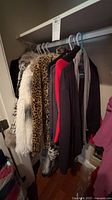 Rack with leopard and ivory faux-fur pieces plus black-red jacket and scarf