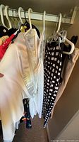 White cardigan, lace top, geometric skirt among assorted garments on hanger