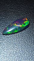 Top view of elongated black opal showing multicolor flashes