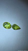 Pair of yellow-green faceted sphene gemstones on neutral background