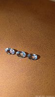 Three oval cut blue gemstones on brown background