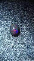 oval black opal cabochon showing red, green and blue flashes