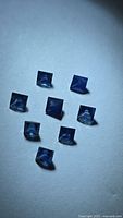 Eight square blue sapphires arranged on light surface