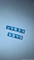 Two rows of square blue gemstones under neutral lighting