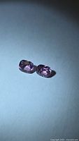 Two cushion-cut pink spinels side by side under spotlight