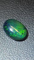 Top view of oval Ethiopian black opal showing green play-of-color