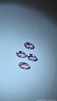 Four oval sapphires under spotlight showing color and faceting