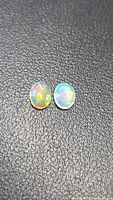 Pair of oval faceted opals on black background