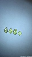 Four yellow-green leaf-cut tourmalines on white background