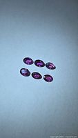 Six oval purple-red rubies on neutral background