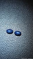 Pair of oval blue star sapphires on textured surface